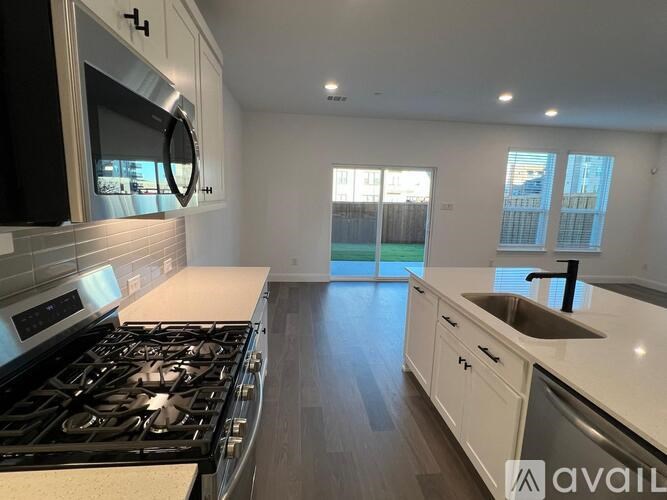 A kitchen with a black stove top oven and white cabinets.