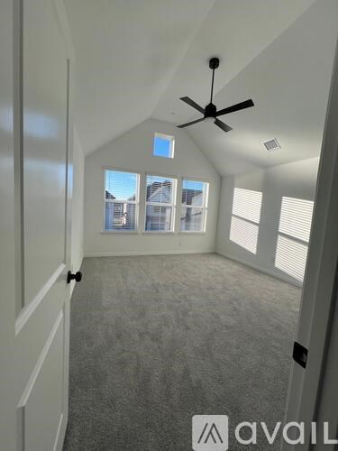 A room with a ceiling fan and a window overlooking a cityscape.