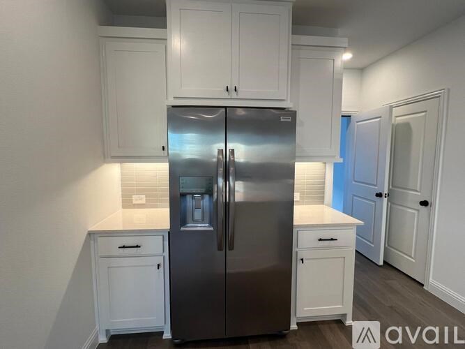 A modern kitchen with a stainless steel refrigerator and white cabinets.