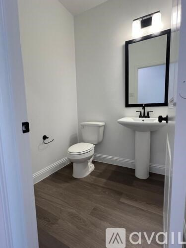 A bathroom with a toilet, sink, and mirror.