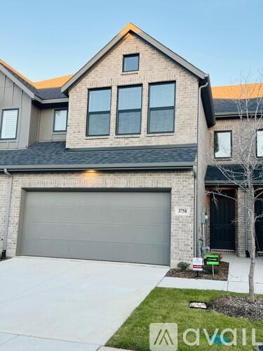 A two-story house with a garage and a driveway in front.