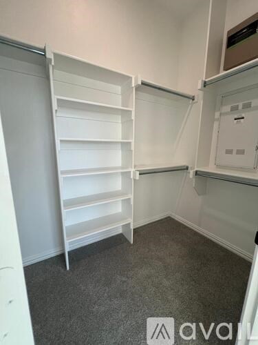 A white shelving unit in a room with grey carpet.