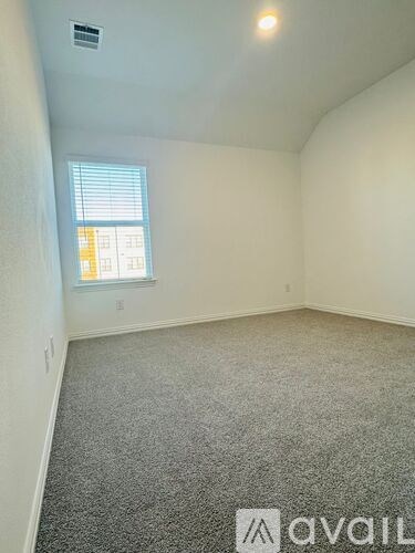 A room with a carpeted floor and a window with blinds.