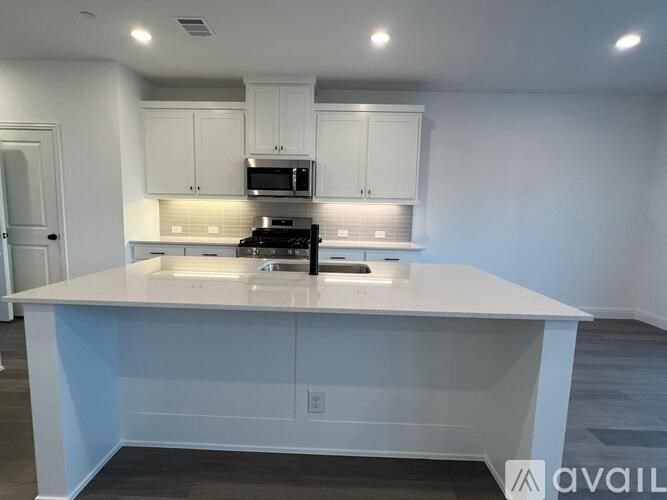 A kitchen with white cabinets and a white island with a sink.