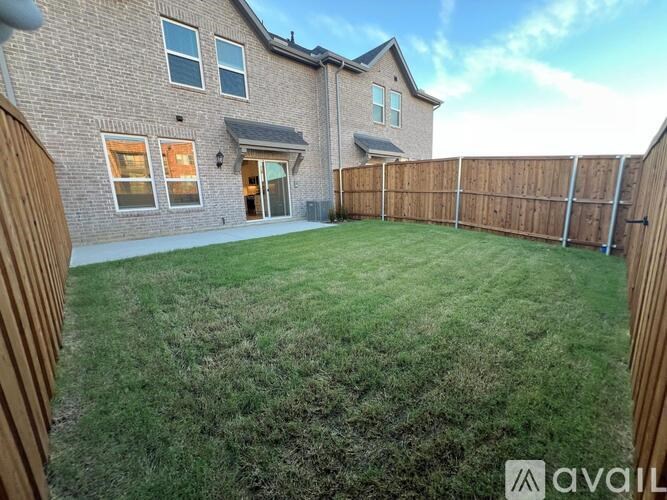 A backyard with a wooden fence and a house in the background.