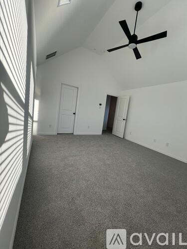A room with a ceiling fan and sunlight streaming in through the window.