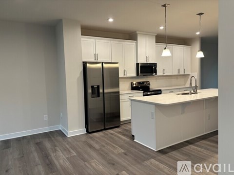 A kitchen with white cabinets and a black refrigerator.