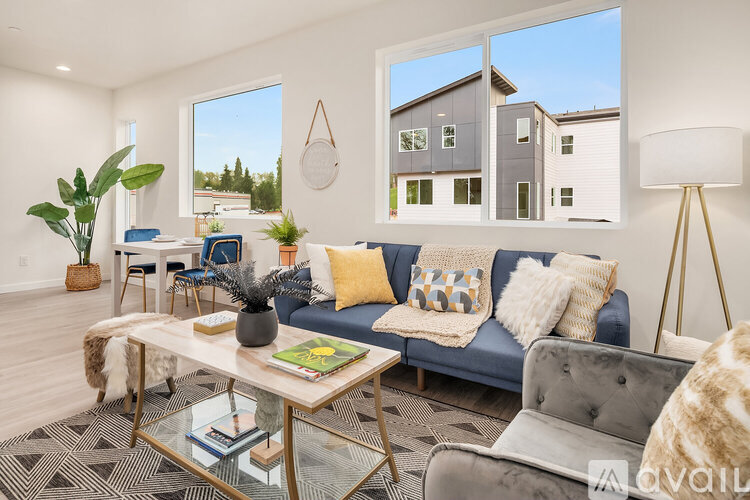 A modern living room with a grey couch, a glass coffee table, and a large window.