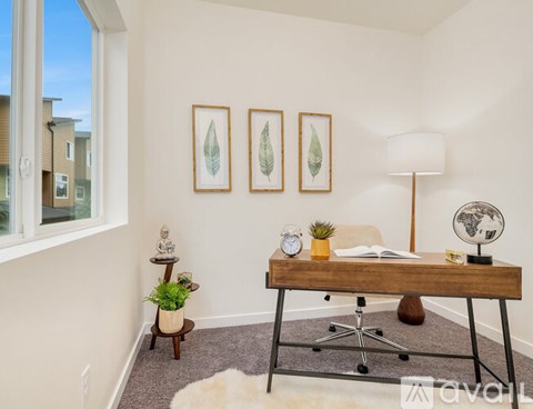 A room with a desk, chair, and three framed leaves on the wall.