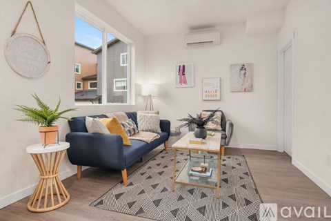 A living room with a blue couch, a wooden table, and a rug.