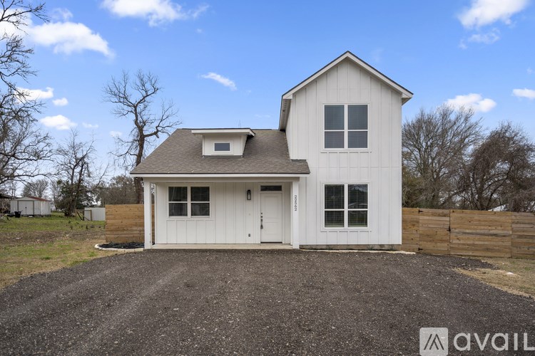 A white house with a gravel driveway in front.