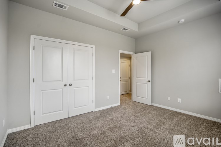 A room with a carpeted floor and two white doors.