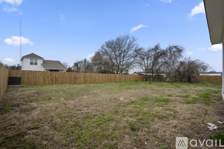 A backyard with a wooden fence and a house in the background.