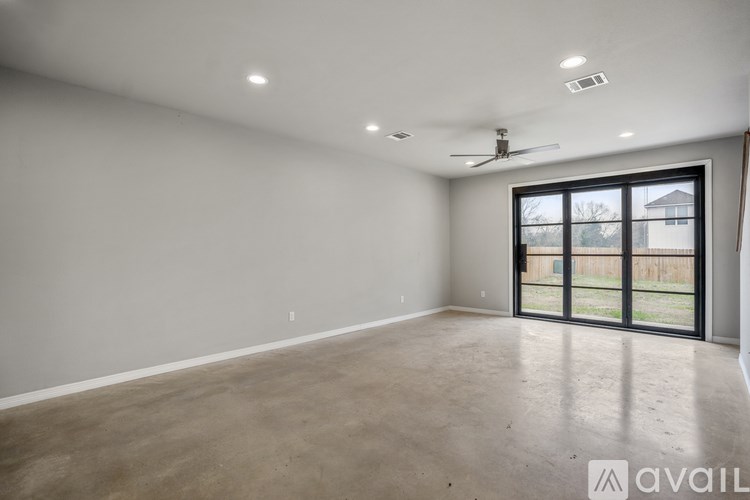 A spacious room with a sliding glass door leading to a backyard.