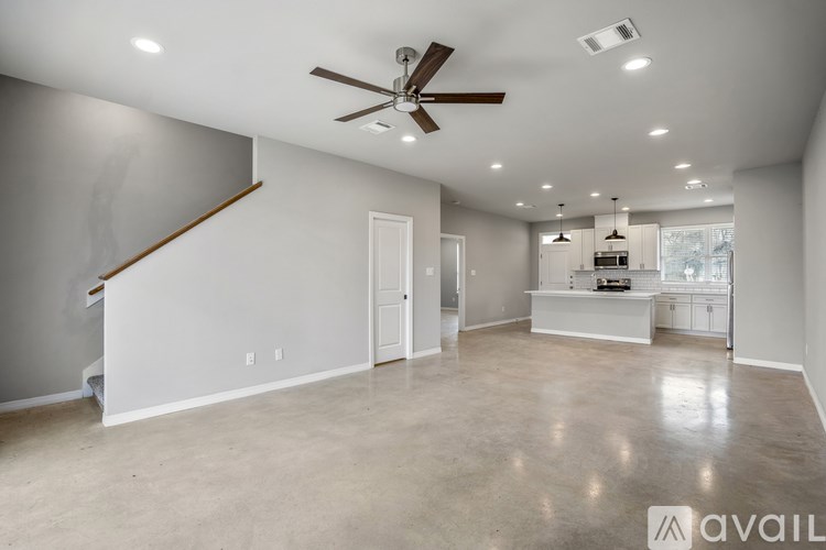 A spacious living room with a ceiling fan and a staircase on the left side.