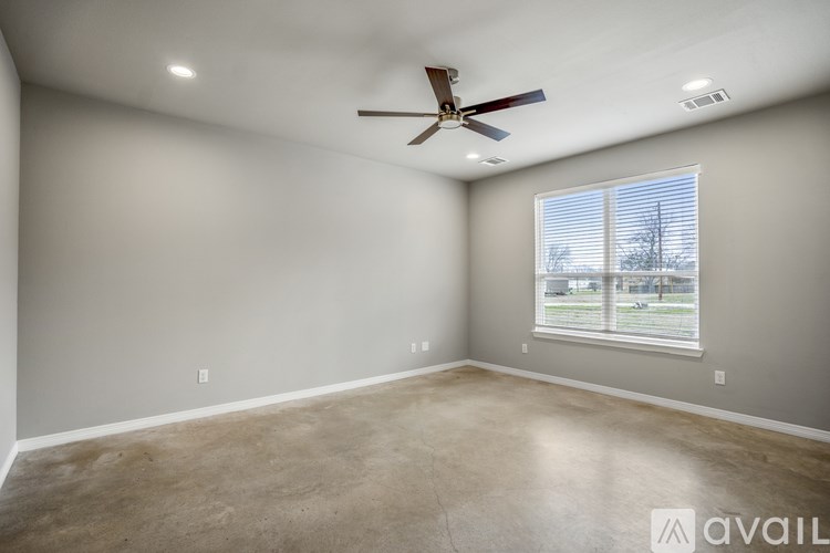 A spacious room with a ceiling fan and a window with blinds.