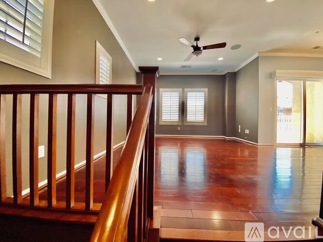 A wooden staircase leads to a room with a ceiling fan.