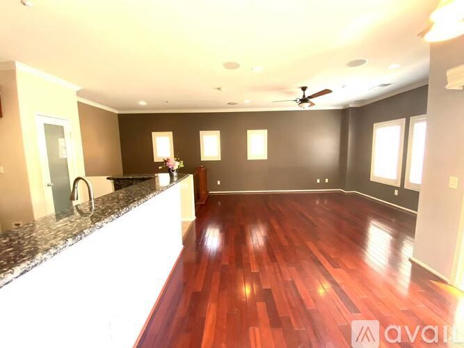 A spacious room with wooden floors and a ceiling fan.