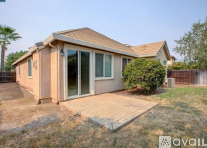 A house with a brown roof and tan walls is for sale.
