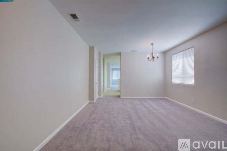 A room with a carpeted floor and a chandelier hanging from the ceiling.