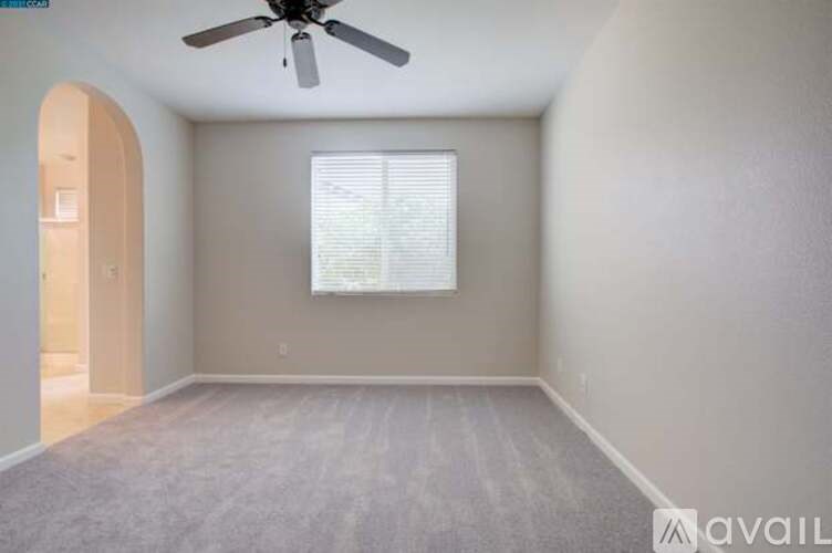 A room with a ceiling fan and a window with blinds.