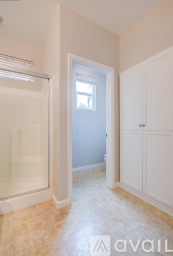 A white bathroom with a glass shower door and a white cabinet.