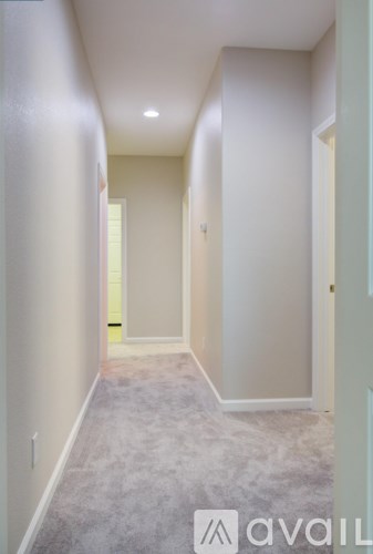 A hallway with a carpeted floor and white walls.