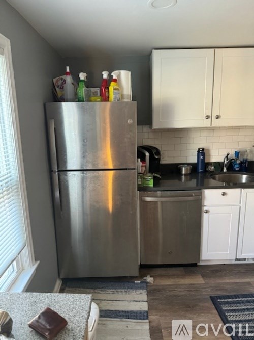 A kitchen with a stainless steel refrigerator and white cabinets.