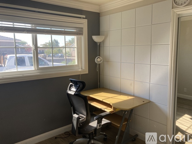 A room with a desk and chair in front of a window.