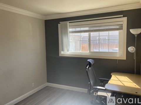 A room with a desk and chair in front of a window.