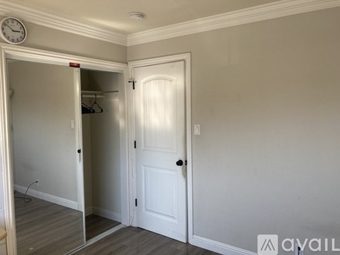A white door is open to a hallway with a clock on the wall.