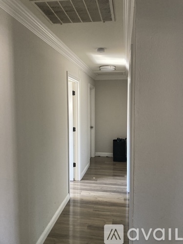 A long hallway with a door at the end and a box on the floor.