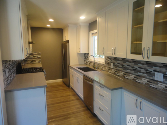 A kitchen with white cabinets and a stone backsplash.