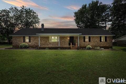 A house with a brick facade stands in a grassy yard.