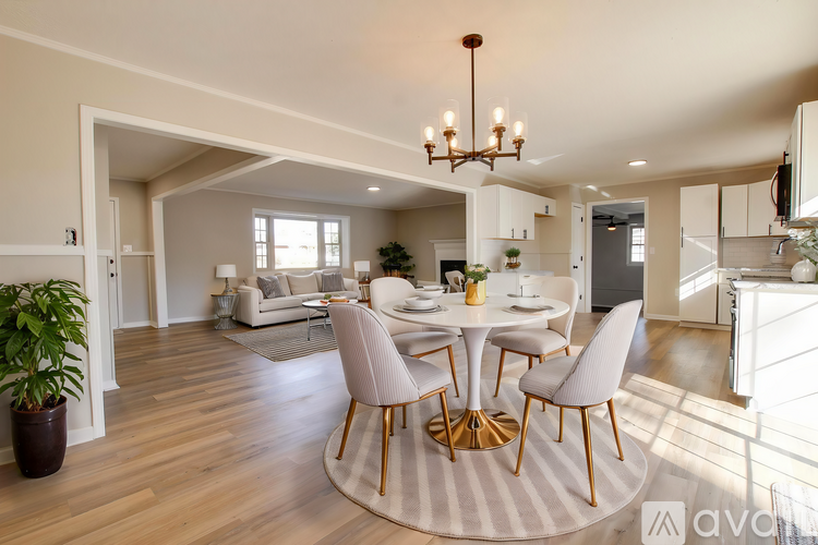 A spacious living room with wooden flooring and a chandelier.