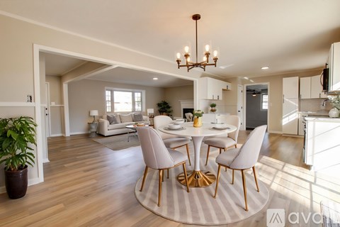 A spacious living room with wooden flooring and a chandelier.