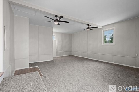 A spacious room with a ceiling fan and a window.