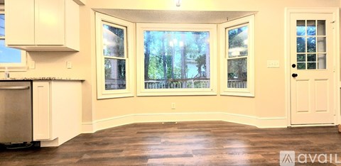 A kitchen with white cabinets and a window with a view of trees.