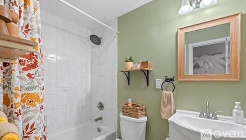 A bathroom with a white tub and a green wall.
