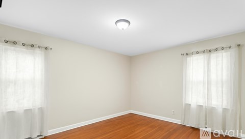A room with wooden floors and white curtains.
