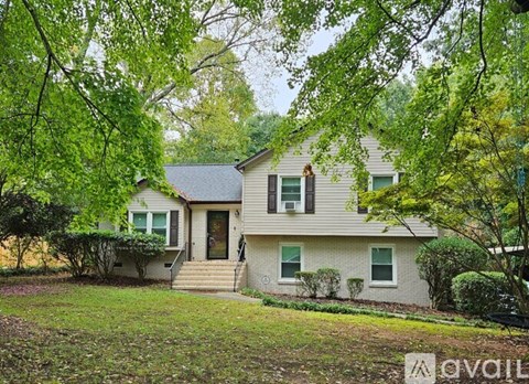 A house with a front yard and trees in the background.