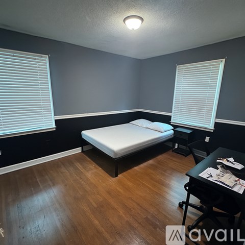 A bedroom with a bed, chair, and painting on the wall.