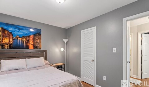 A bedroom with a large bed and a painting of a cityscape on the wall.