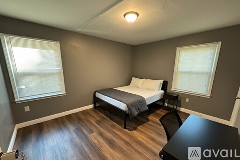 A bedroom with a bed, a dresser, and a television playing a basketball game.