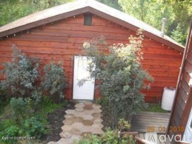 A wooden building with a white door and a small garden in front.