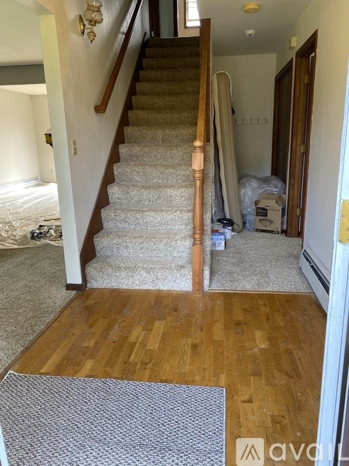 A hallway with a staircase and a door on the right.