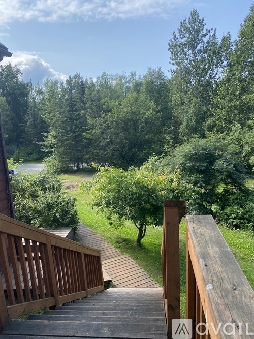 A wooden deck leads down to a grassy area with trees in the background.