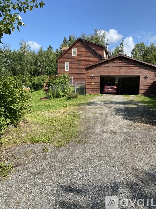A red barn with a garage door is situated in a grassy area.