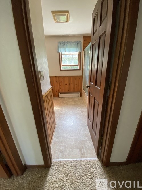 A hallway with a carpeted floor and wooden doors.
