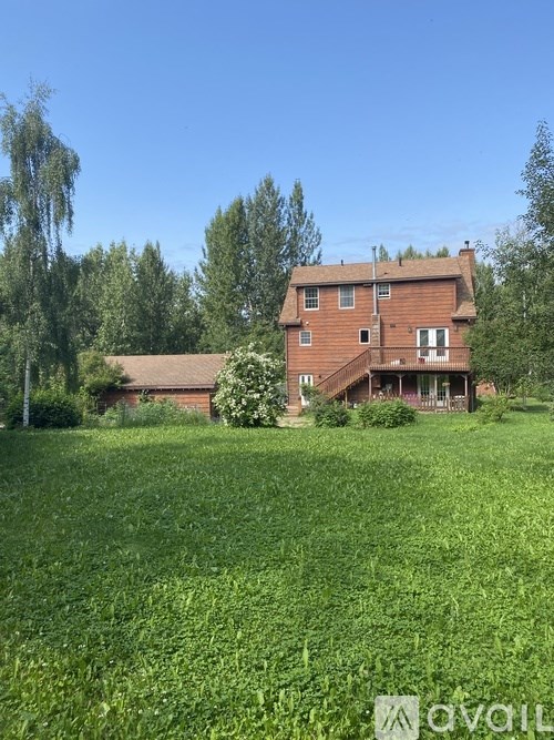 A house with a red brick exterior is surrounded by a green field.